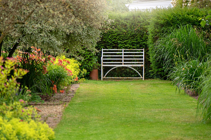 An English summer garden with a wrought iron white seat